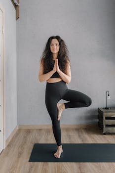 A woman practicing yoga indoors, focusing on balance and mindfulness.