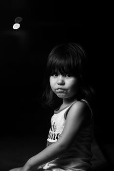 Emotive black and white portrait of a young girl with a pensive expression.