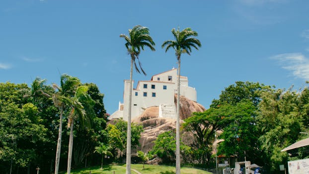 Scenic view of Convento da Penha in Vila Velha, Espírito Santo, surrounded by lush greenery and palm trees.