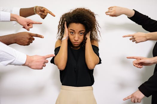 Stressed woman with hands on ears surrounded by pointing fingers, illustrating pressure.