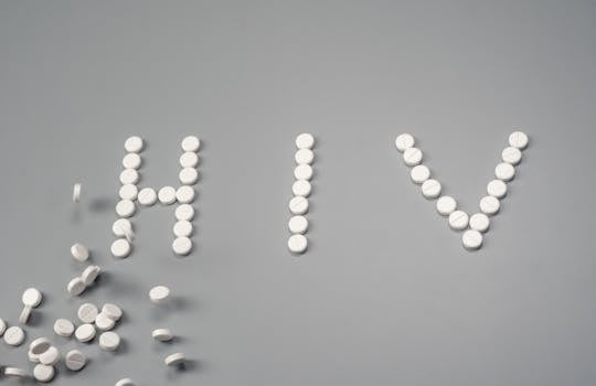 White pills forming the word 'HIV' on a grey background, symbolizing treatment.