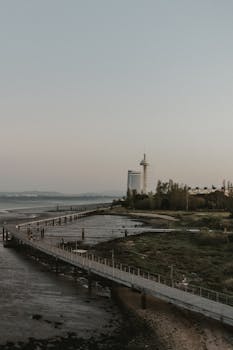 Aerial view of Torre Vasco da Gama in Lisbon, Portugal, with a serene riverside walkway at twilight.