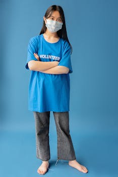 Portrait of a woman wearing a volunteer shirt and face mask in a studio setting.